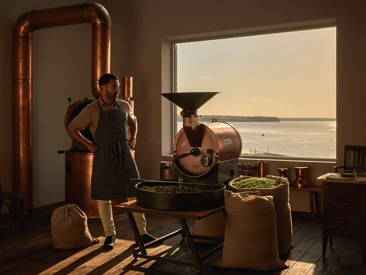 Illustrierte Rösterei mit Kupfertrommel, Rohkaffeesäcken und Blick auf die Ostsee