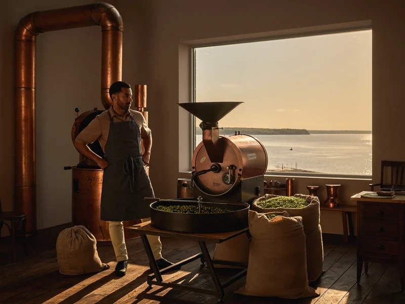 Illustrierte Rösterei mit Kupfertrommel, Rohkaffeesäcken und Blick auf die Ostsee