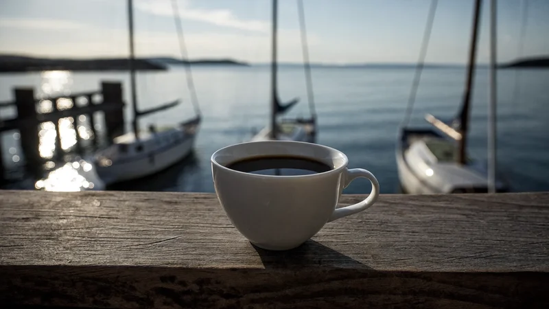Illustration: schwarzer Kaffee auf einem Hafengeländer bei Morgendämmerung